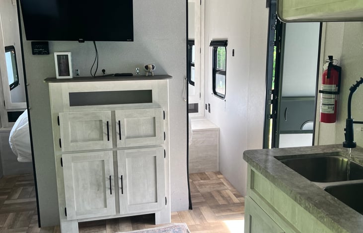 TV by front door and kitchen sink