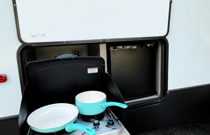 The outdoor kitchen features a two burner stove and another refrigerator for extra food and drink space.