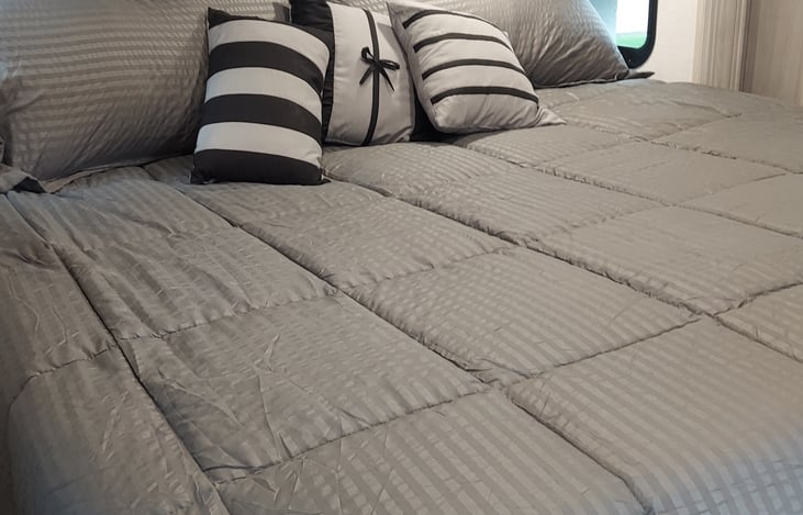 king size bed in bedroom with purple foam cover to make it extra comfortable.