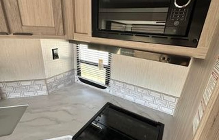 Three Propane Burner stove top and oven!. with a microwave right above.