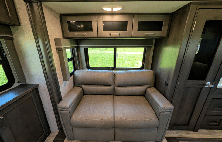 Gourmet galley & rear den retreat! Includes a 12 cu ft fridge, pantry, stove/oven, dual sofas, theater seats, 50" TV, electric fireplace, and 3 slides for spacious high-end living.
