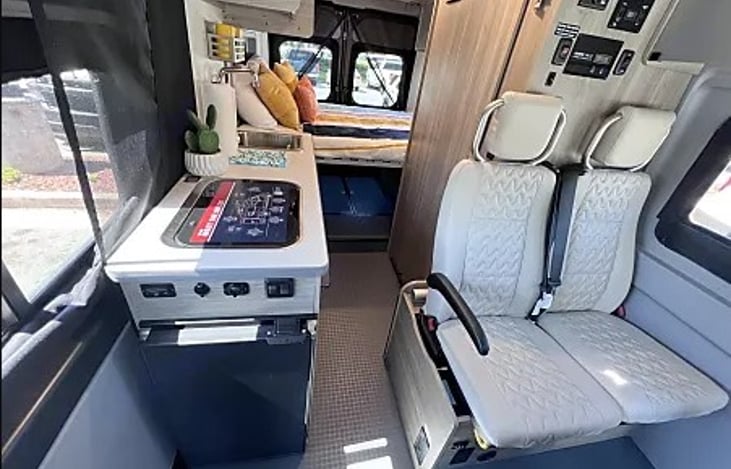 Immerse yourself in the welcoming ambiance of our RV's kitchen area as you enjoy a breathtaking view of the back.