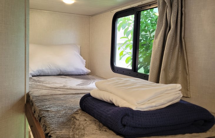 Top bunk with lamp and 12v USB wall ports for charging electronics.