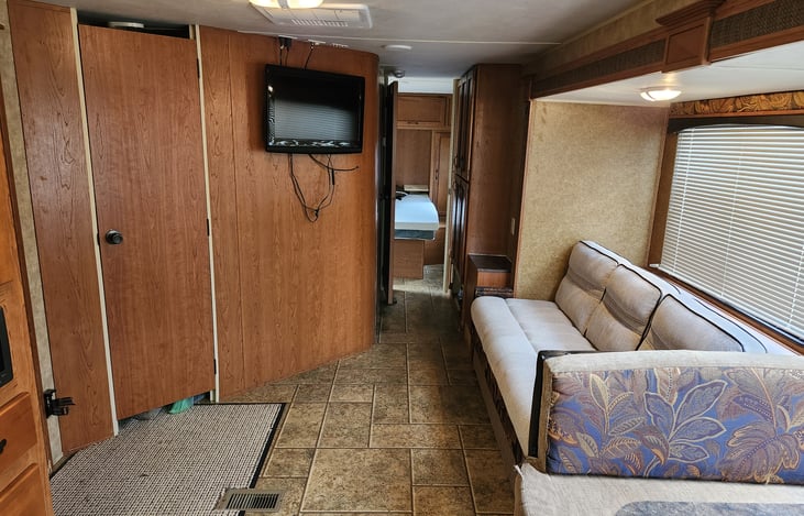 Looking to back of camper. Closet and main door to left. Jackknife sofa on right. View through hallway to back bedroom.
