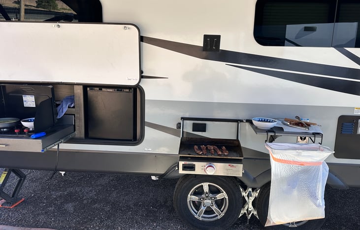 Outdoor Kitchen (Inside kitchen too) with Beverage Cooler Fridge, 17 in griddle, 2 Burner Stove, Water Hose for rinsing off, and Small outside shelf.  This set-up keeps the cooking mess outside.