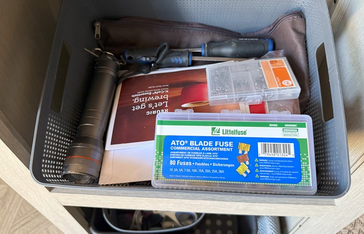Flashlight, screwdrivers, manuals, and fuses stored in the kitchen island