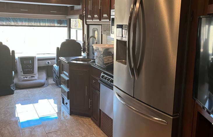 Fully equipped kitchen with residential fridge, 3-burner cook-top, convection microwave, solid-surface counters, pantry, and plenty of cabinet space for cooking on the go.