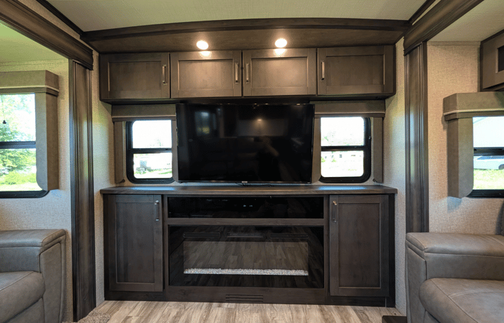 Gourmet galley & rear den retreat! Includes a 12 cu ft fridge, pantry, stove/oven, dual sofas, theater seats, 50" TV, electric fireplace, and 3 slides for spacious high-end living.