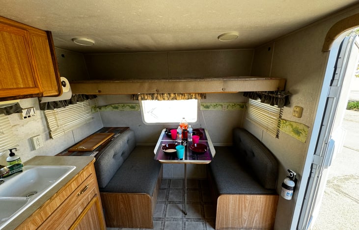 The overhead cabinet above the eating booth becomes a bed.