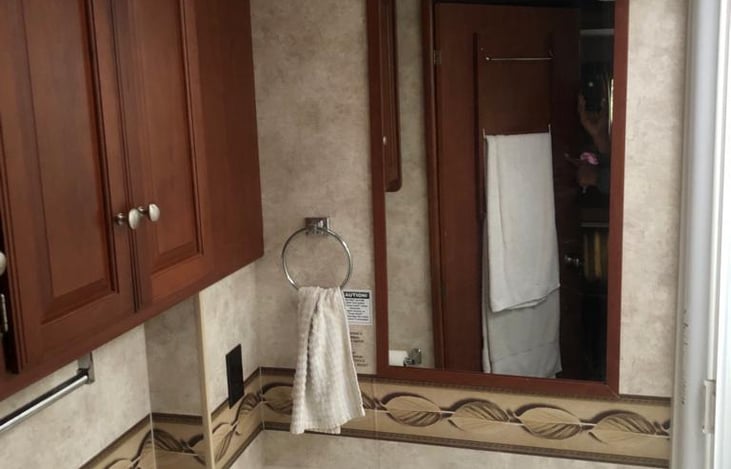 Spacious bathroom with shower, sink, toilet and extra cabinets for storage.