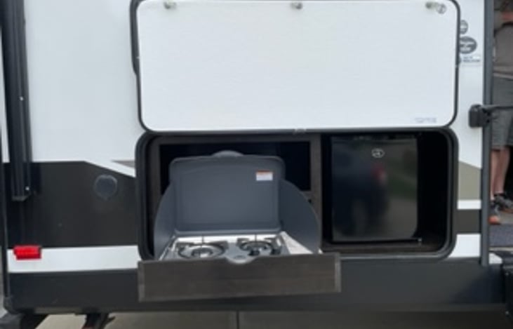 exterior kitchen with two burner stove top and a small fridge