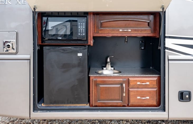 Outdoor kitchen with sink, microwave & mini fridge.. Camp chef griddle available as an add on (runs off on-board propane).