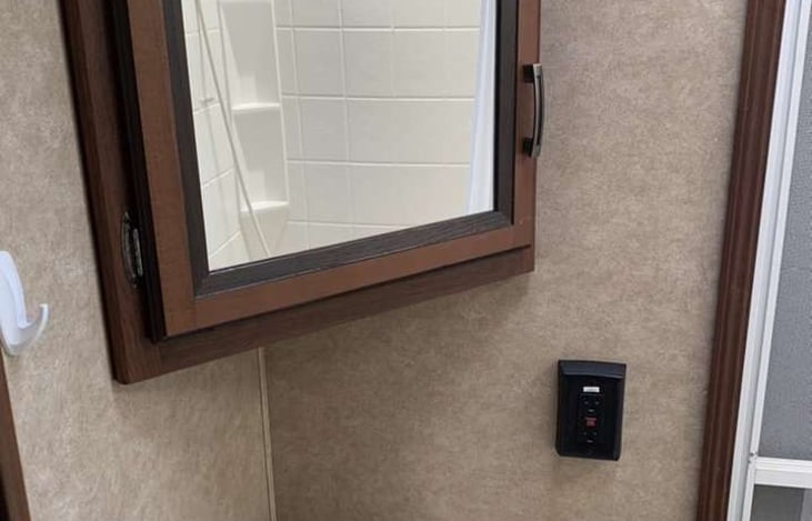 Bathroom has a mirror with storage behind it as well as below the sink