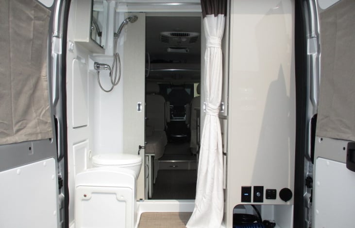 cassette style toilet, shower, sink at rear of unit by back doors