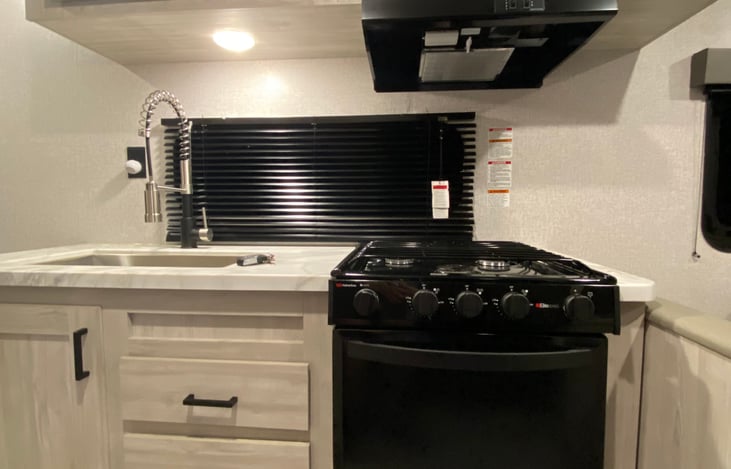 3 burner stove top & oven with hood and microwave above.