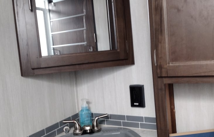 Sink with medicine cabinet and storage located over the toilet.