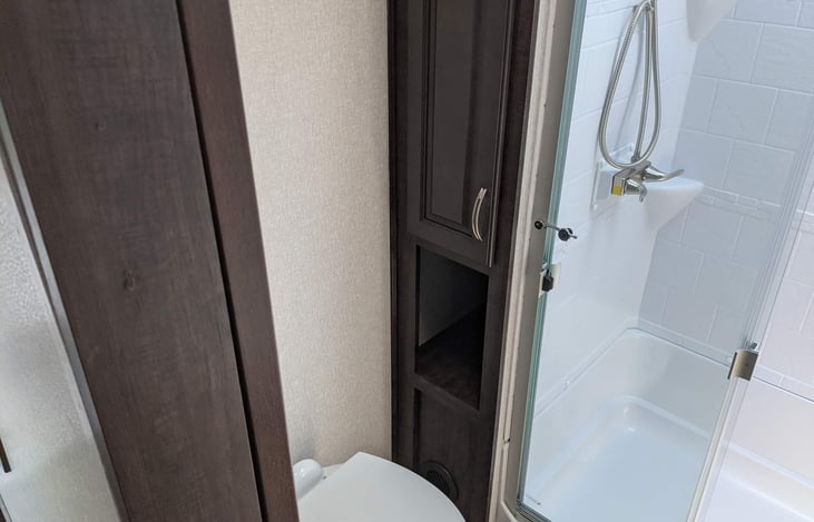 Bathroom with walk-in shower and cabinet to store towels and other items.