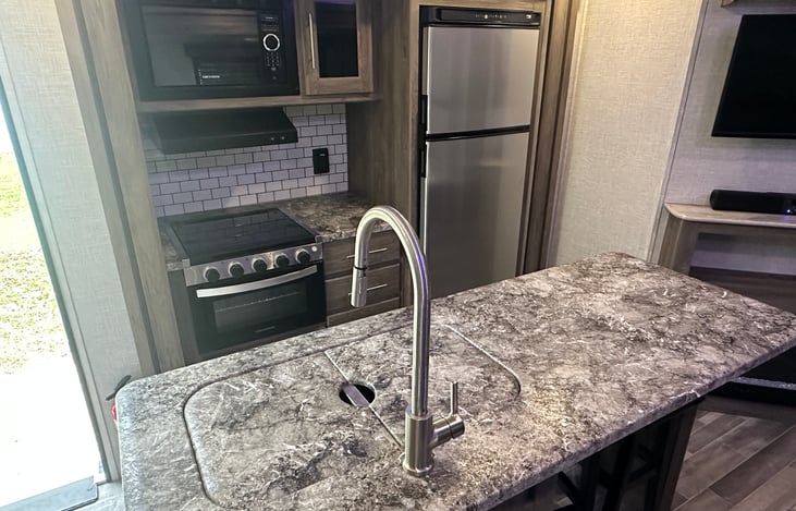 Gas range and oven, vent hood, refrigerator and freezer, kitchen island with breakfast bar.