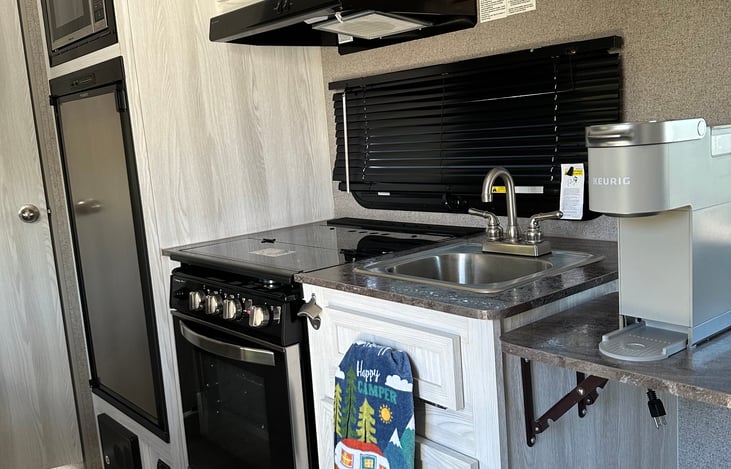 Full functioning kitchen.  Contains microwave, refrigerator, stove, oven, overhead fan and overhead light, sink, fire alarm and overhead storage.