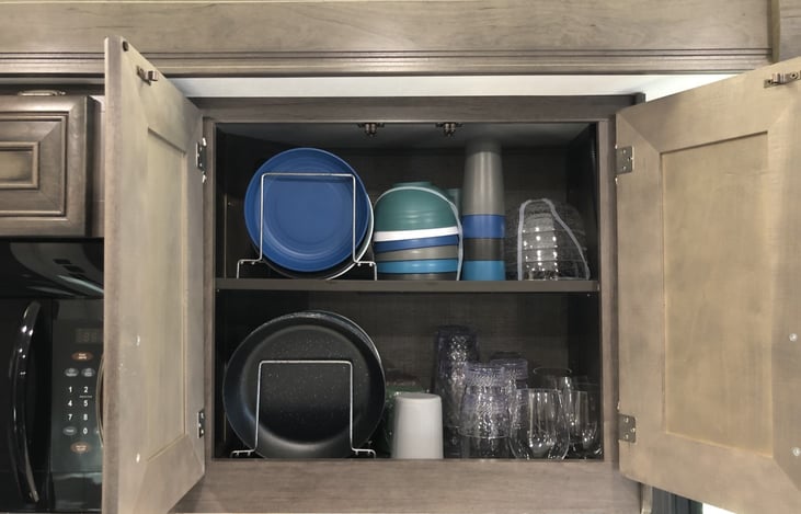 Kitchen cabinets fulls stocked with dishes, bowls, glasses, etc. All are microwave safe.