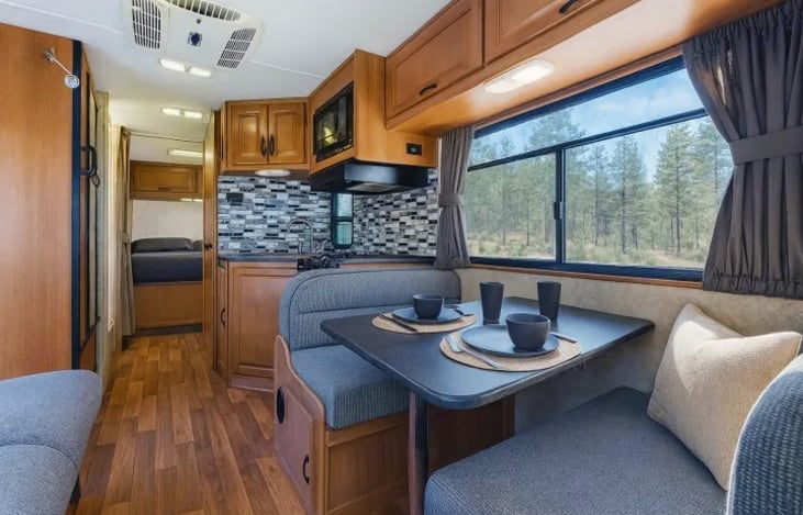 Bright and comfortable living area with sofa and panoramic windows — relax in your family-friendly RV after exploring national parks or cruising the Las Vegas Strip.