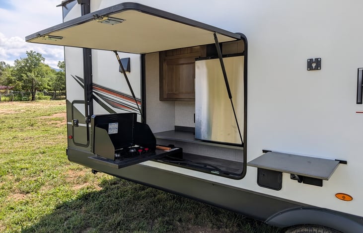 Features a convenient outdoor kitchen with a mini-fridge, 2-burner gas cooktop, and storage! Perfect for cooking outside under the 21-ft awning.