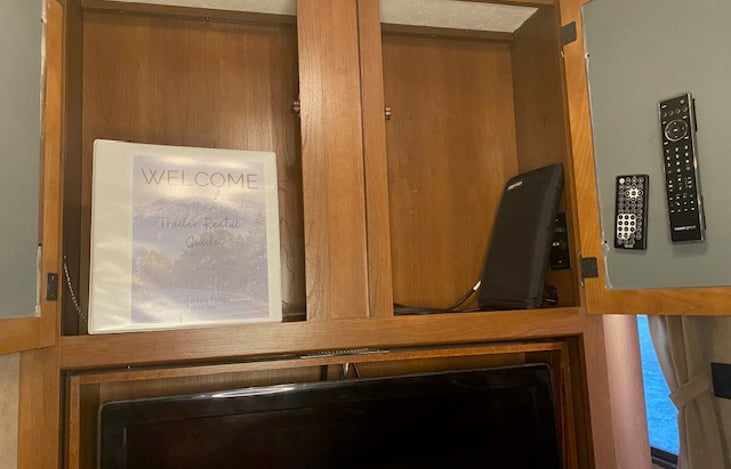 Storage above TV. welcome binder, assorted DVDs and remotes