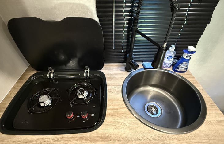 Propane stove top burners and deep well stainless kitchen sink.