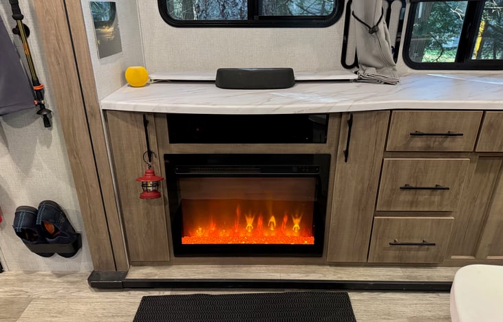 Electric fireplace adds warmth and a cozy atmosphere on cooler evenings. The TV retracts neatly into the cabinet when not in use.