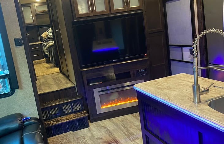 Main living space, electric fireplace, TV, and front door.