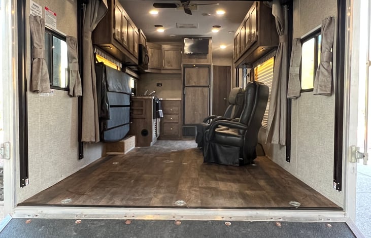 Toy hauler garage entrance showing furniture in retracted positions. Garage foot print is 11'8" x 5'6"(140 inches x 66"). Fits one 2-seat UTV or one standard width 4-seat UTV.