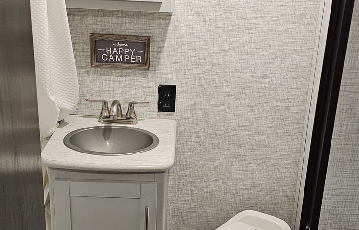 Enclosed restroom with sink, shower, and toilet.