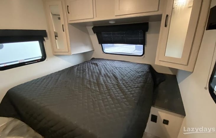 Master bedroom with queen size bed, overhead storage cabinets, and mirrored wardrobe cabinets