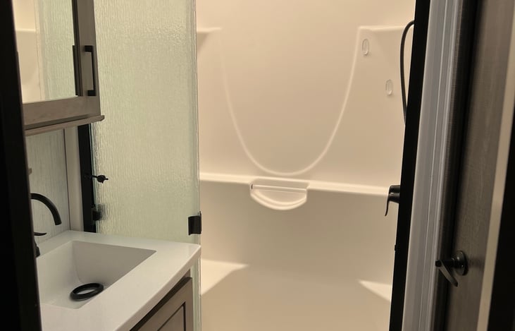 Spacious shower with external full sized sink and separate toilet.