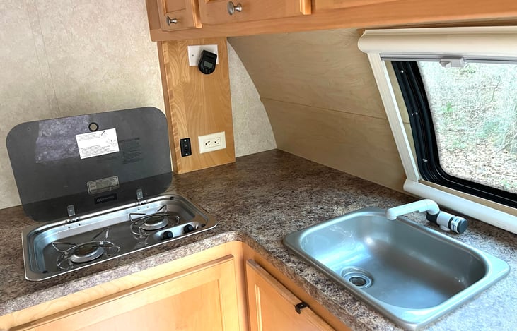 Two burner stove and sink.  Please note that to have running water, a water source needs to be hooked up to the trailer, such as a campsite water hose. No grey water tanks, so no need to empty.