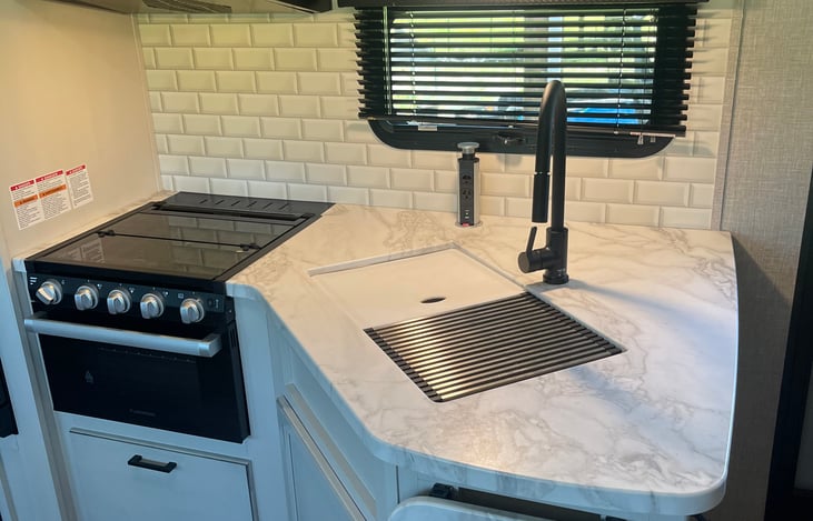 Gas stove. Oven. Sinks.  Storage with place settings for 4. Pots/pans utensils in storage.