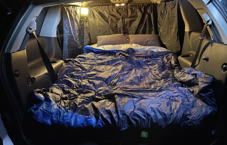 Here I have the 2 sleeping bags opened up as a comforter.  The two memory foam camping pillows have soft removable covers that are washed after use. 

The divider and side curtains provide privacy.