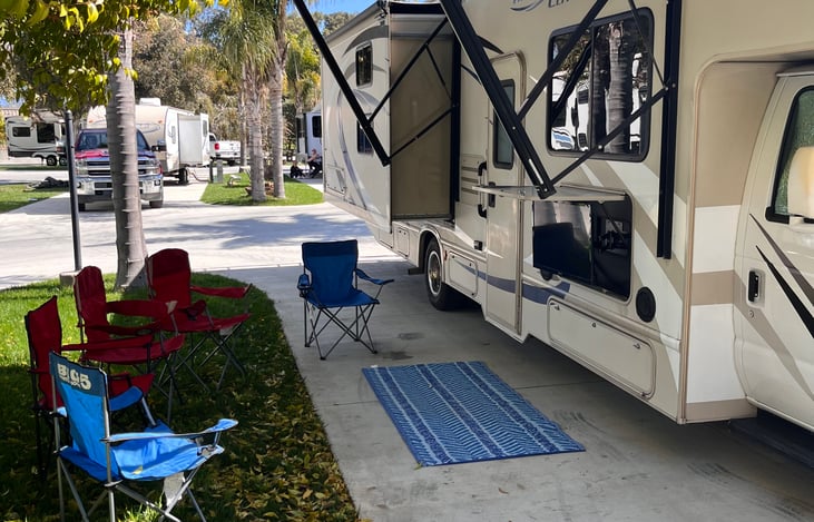 The passenger side of the RV has a slideout, awning with night lights, and an outdoor TV.