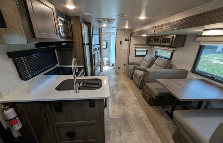 Spacious open-concept living area w/ dual recliners, TV & fireplace. Full kitchen features a residential fridge, 3-burner stove, oven, microwave, deep sink & booth dinette! Natural light throughout.