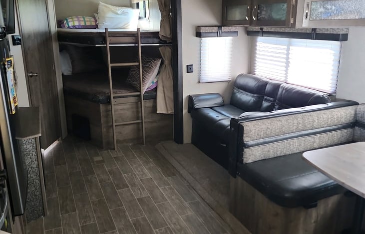 Dining table that can be converted to bed, couch, and set of bunks. Bathroom to the left with shower.