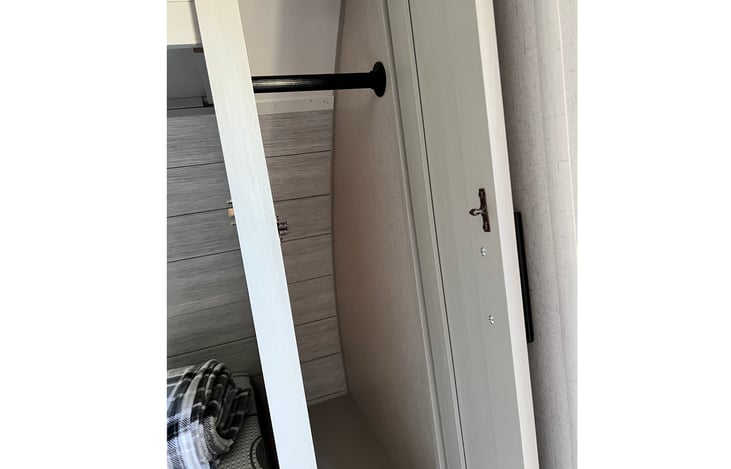 clothes closet with bar for hanging clothes next to couch/Murphy bed