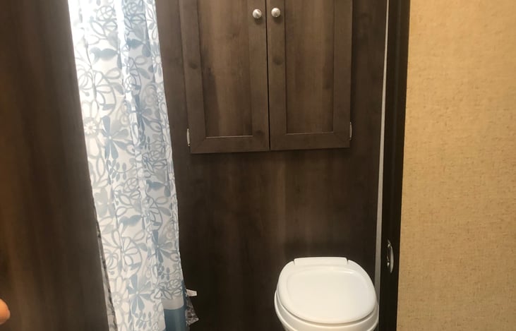 Storage cabinet above flush toilet.  Shower/tub to the left