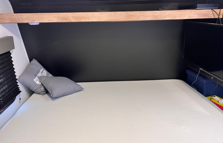 Queen size bed in the front with an upgraded mattress.