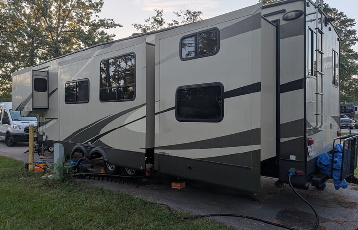 Left-rear, showing the master bedroom, super slide, and rear bunkhouse slideouts. Water, electric, and sewer hoses and connections are provided with the rental. The RV is on 50 amp.