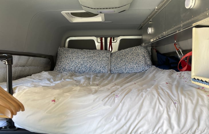 Our sleeping set up with large duffel bags for  clean and dirty laundry on the right of the mattress. Lots of overhead storage