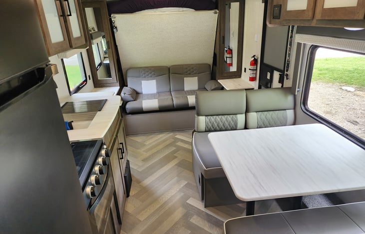 A lovely dinette with a huge campsite window. A sofa for relaxing, and a single-piece murphy bed. Note the kitchen with a residential-sized fridge. 

So much in a lightweight trailer.