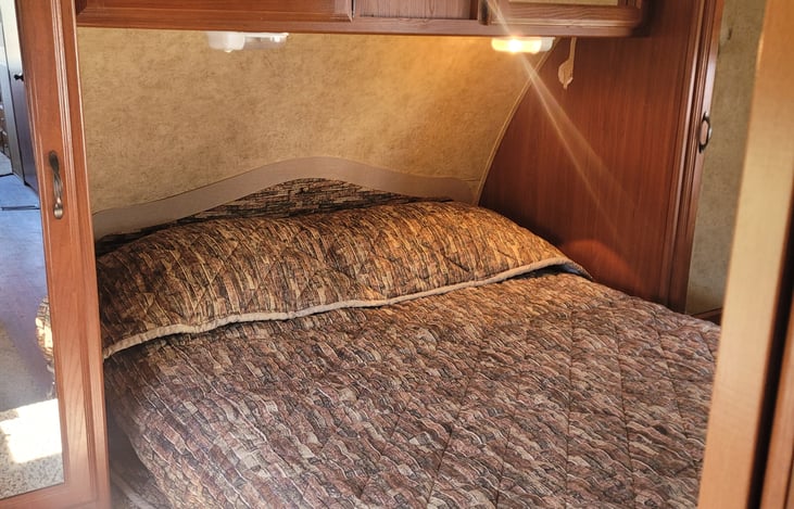 Small master bedroom with cupboards above bed and beside the double bed. One sliding door on each side of the bed.