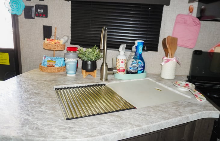 Kitchen sink with drying rack and cutting board.