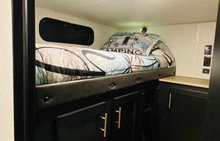 Full Sized bed with linens and pillows, overhead spotlight.