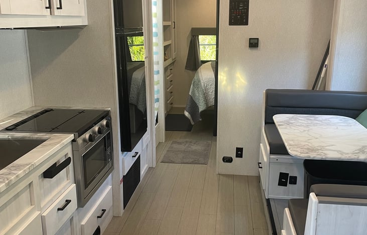 The kitchen dinette area lowers to sleep two additional people. The stove is propane, and the microwave is electric with a convection oven.